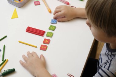 Küçük çocuk basit matematik egzersizleri yaparak ilkokula hazırlanıyor. Omzundan vurulmuş.