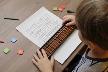 Küçük çocuk abaküs puanıyla basit matematik alıştırmaları yapıyor. Zihinsel aritmerik. Omuzdan görünüm