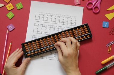 Zihinsel aritmetik ve matematik kavramı: kırmızı arkaplanda renkli kalemler ve kalemler, sayılar, abaküs puanları