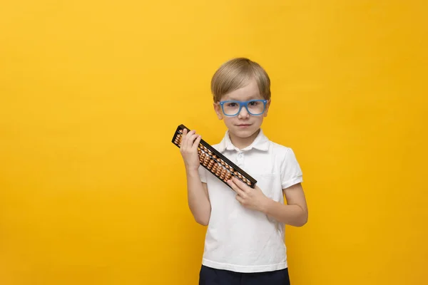 Cute little school boy in glasses holding abacus on yellow background. Mental arithmetic — 스톡 사진