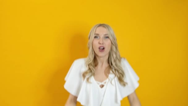 Gyönyörű szőke meglepett nő kifejezni boldogság elszigetelt sárga háttér — Stock videók