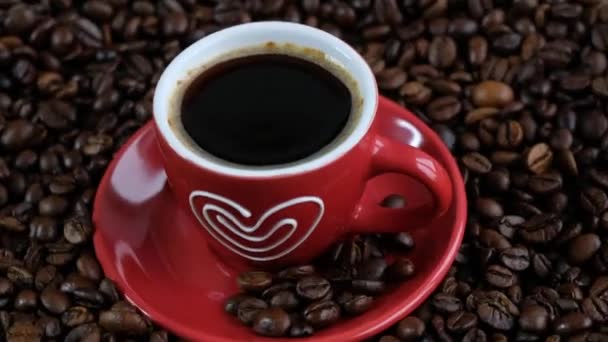 Donkere koffiekorrels en rode beker. Koffiebonen draaien. Sluiten van zaden van koffie. — Stockvideo