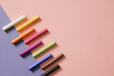 Pembe geometrik arka planda renkli pastel boya kalemleri ve fotokopi alanı. Sanat, çizim konsepti