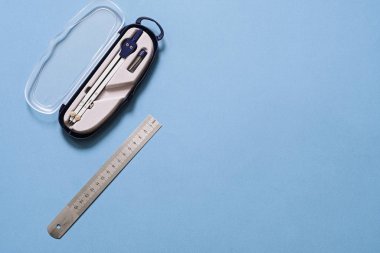 Mavi arkaplanda izole edilmiş pusula ve metal cetvel çizimi, kopyalama alanı. Geometri, matematik, mühendislik