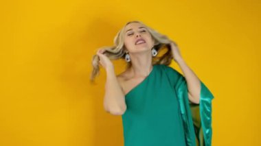 Sarı arka planda dans eden güzel, mutlu sarışın kadın.