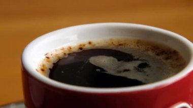 Red cup with hot black coffee rotating, close up macro