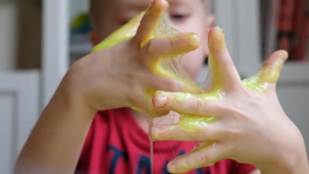 Kleine jongen peuter die speelt met lichtgroen slijm. Sluiten. — Stockvideo