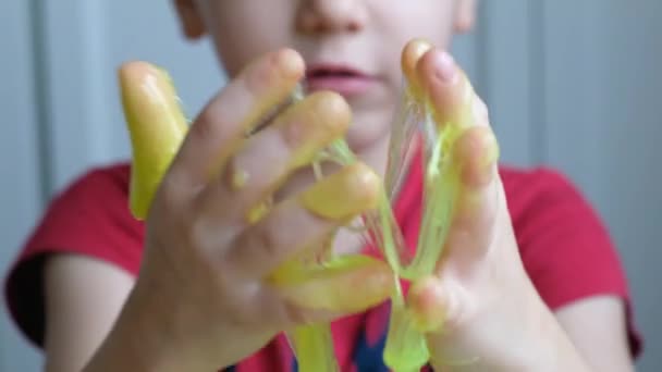 Egy kisgyerek, aki világoszöld nyálkával játszik. Közelről. — Stock videók