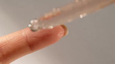 Bir damla hidrasyon serumu, yağ, beyaz arka planda bir parmakta yüz derisi için vitamin. Cilt Bakımı Özü