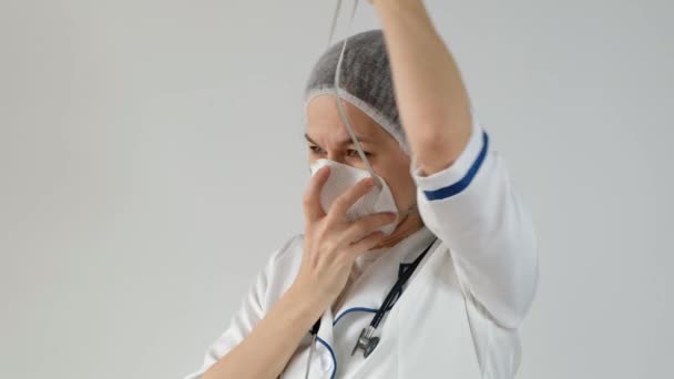 Női orvos visel eldobható csésze és szűrő maszk légzőkészülék a szennyezés elleni védelem fehér háttér. — Stock videók
