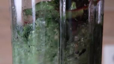 Green detox smoothie mixing in a blender, close up