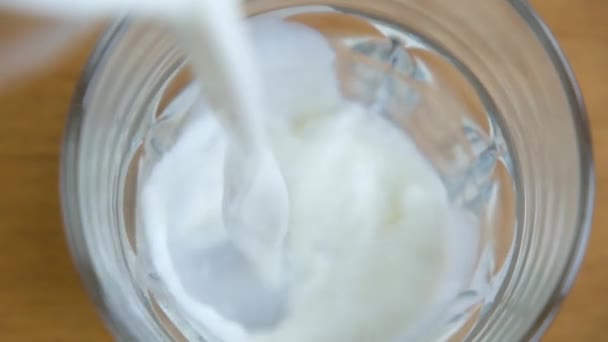 Closeup of pouring glass of milk , high angle view — Stock video