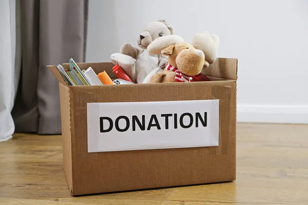 Donation concept: box full of books and toys on the floor. Donate for children please