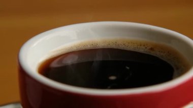 Red cup with hot black coffee rotating, close up macro