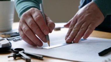 Mimarlar masası: çizimler, cetvel ve diğer çizim araçları. Mühendis çizimlerle çalışır, yakın plan..