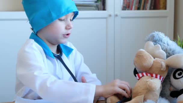Pequeño niño lindo jugando médico con estetoscopio y sus juguetes — Vídeo de stock