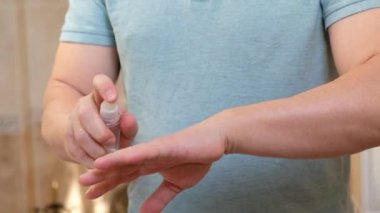 İnsan, bakteri ve koronavirüsten korunmak için ellerine antiseptik sprey sıkar..