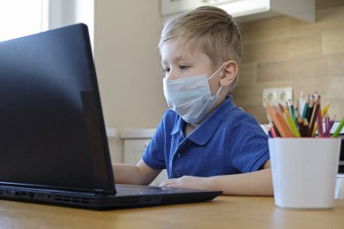Uzaktan öğrenme çevrimiçi eğitim. Beyaz çocuk evde ödev yaparken epidemi korona virüsünü karantinaya almış.