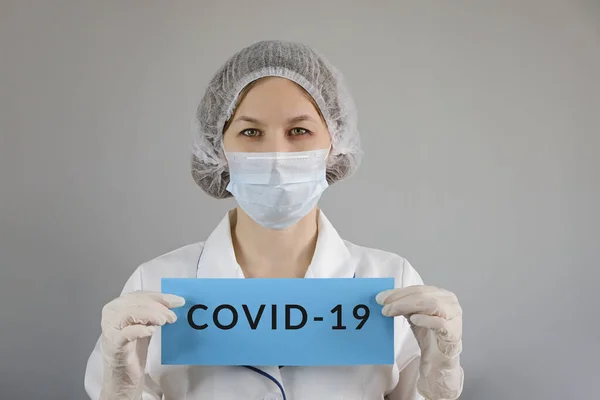 Tıp çalışanı portresi. Korumacı yüz maskesi takmış, elinde COVID-19, Corona virüsü olan kendinden emin bir kadın doktor.