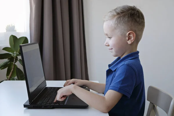 Educación a distancia en línea. Lindo chico caucásico haciendo la tarea en un ordenador mientras que la cuarentena de epidemia virus corona — Foto de Stock
