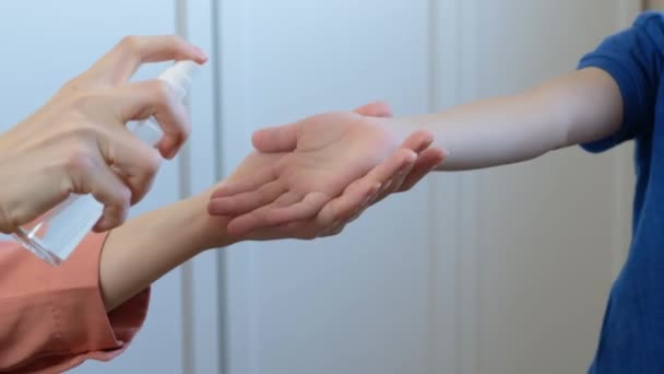 Kinderhygiëne: vrouw die antiseptische spray gebruikt om de handen van kinderen te reinigen en beschermt tegen virussen en bacteriën, close-up — Stockvideo