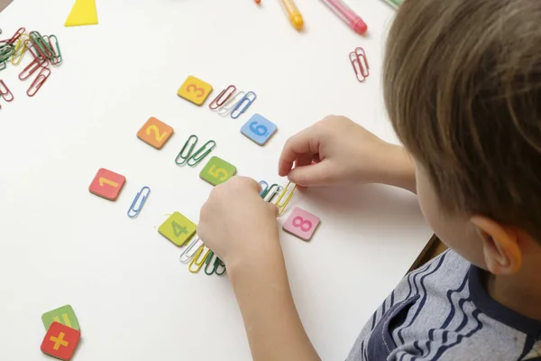 Küçük çocuk basit matematik egzersizleri yaparak ilkokula hazırlanıyor.