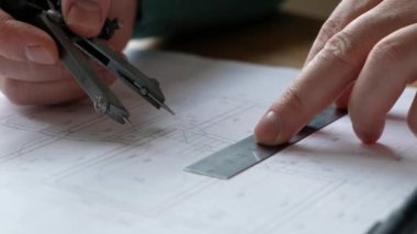 Mimarlar masası: çizimler, mezura, cetvel ve diğer çizim araçları. Mühendis çizimlerle çalışır, yakın plan..