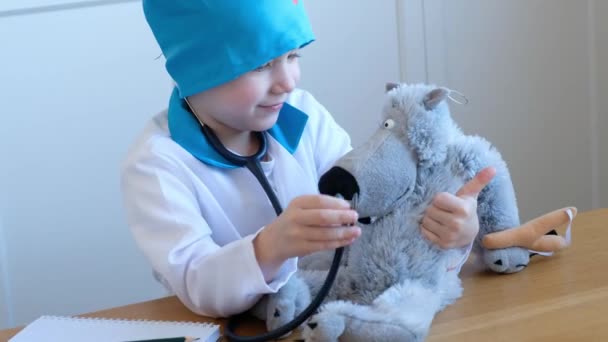 Маленький милый мальчик играет в доктора со стетоскопом и его игрушками — стоковое видео