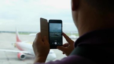 Havaalanı terminalinde uçağa cep telefonuyla ateş eden adam uçağa binmeyi bekliyor..