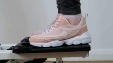 Kadın ayağını kapat, spor salonundaki ayak egzersizi makinesine çalış, tahta zemine basma makinesi tak..