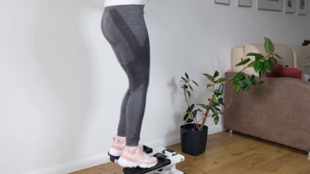 Close up womn legs working out on the stepper exercise machine at home, stepper machine on the wooden floor. — Stock Video