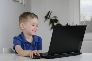 Küçük çocuk karantina sırasında evde oturur ve internet okulunda bilgisayar kullanarak ders çalışır..