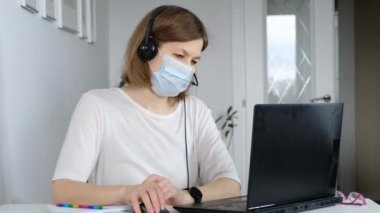 Bir kadın karantina sırasında evinde oturur ve bilgisayar kullanarak internette çalışır. Kişisel tecrit