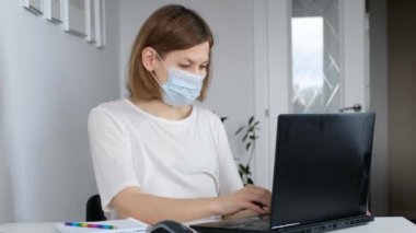 Bir kadın karantina sırasında evinde oturur ve bilgisayar kullanarak internette çalışır. Kişisel tecrit