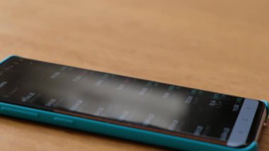 Finans piyasasındaki akıllı telefonları kontrol eden erkeklerin yakınlaşması. Akıllı telefon ekranında borsa grafikleri.