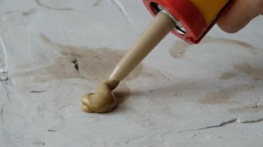 Teknisyen elinde tutkal tabancasıyla silikon yapıştırıcı ile bir şeyleri tamir edip tamir ediyor. Kapatın. Kurulum veya yenileme iç konsepti