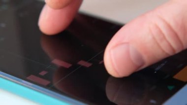 Finans piyasasındaki akıllı telefonları kontrol eden erkeklerin yakınlaşması. Akıllı telefon ekranında borsa grafikleri.