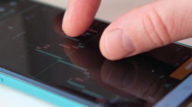 Finans piyasasındaki akıllı telefonları kontrol eden erkeklerin yakınlaşması. Akıllı telefon ekranında borsa grafikleri.