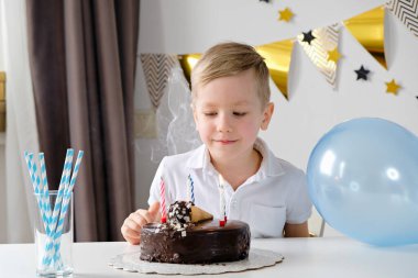 Mutlu çocuk doğum gününü yalnız kutluyor ve pastaya mum üflüyor.