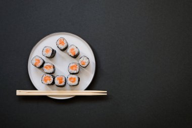 House şekilli suşi ruloları, siyah arka planda çubuklarla fotokopi alanı ile birlikte.