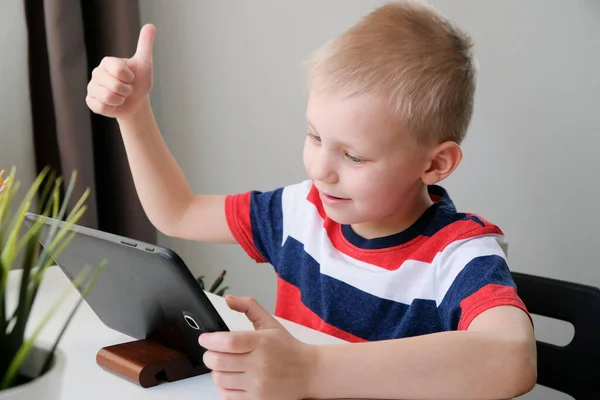 Educación a distancia en línea. Lindo chico caucásico haciendo la tarea con la tableta PC en casa, mientras que la cuarentena del virus de la corona epidemia — Foto de Stock