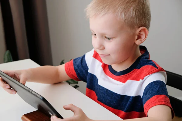 Educación a distancia en línea. Lindo chico caucásico haciendo la tarea con la tableta PC en casa, mientras que la cuarentena del virus de la corona epidemia — Foto de Stock