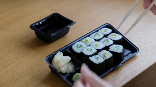 Dodávka odnést jídlo koncept: žena jíst sushi rolky z plastové krabice, zblízka — Stock video
