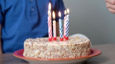 Doğum günü pastasında mum üfleyen tanınmamış çocuk, kapat.