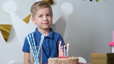 Mutlu çocuk tek başına doğum gününü kutluyor ve pastaya mum üflüyor.