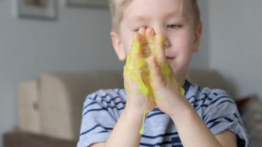 Açık yeşil sümükle oynayan sevimli çocuk. Kapat.