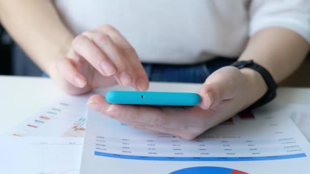 Kvinna hand med smartphone, business diagram på ett bord, närbild — Stockvideo