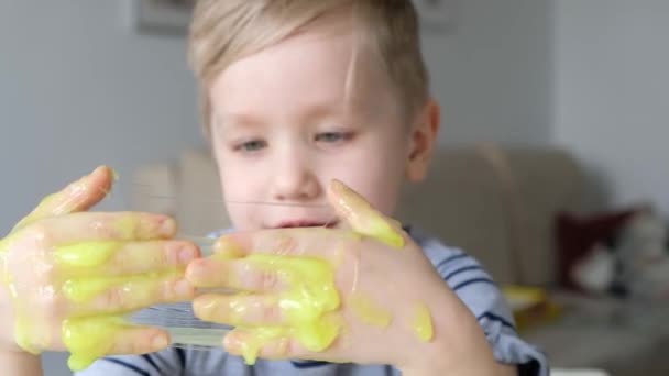 Söt pojke leker med ljusgrön slem. Närbild — Stockvideo