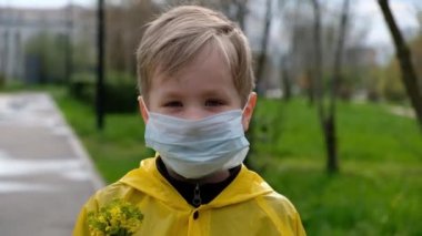 Sağlık maskeli çocuk dışarıda kameraya bakıyor. Karantina, sosyal mesafe, alerji konsepti