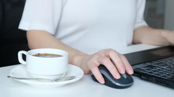 Неузнаваемые женщины руки, работающие на клавиатуре ноутбука и пьющие кофе, крупным планом — стоковое видео